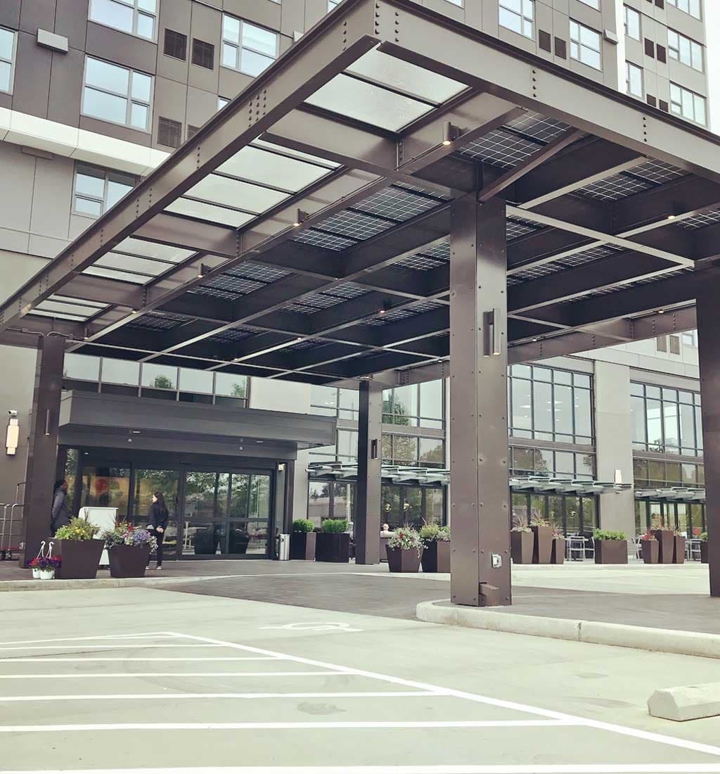 A glass solar canopy sheltering the entry drive of a modern building