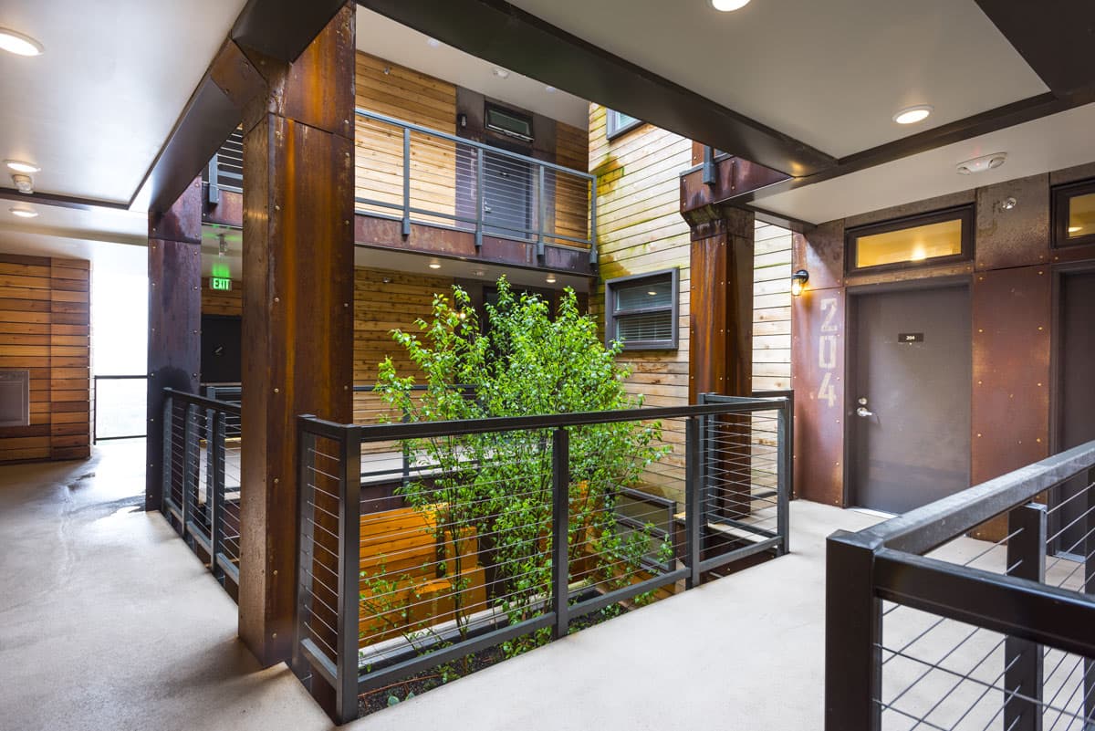 Brooklyn Yard corridor in Portland with wood and steel finishes, cable railings and a courtyard tree