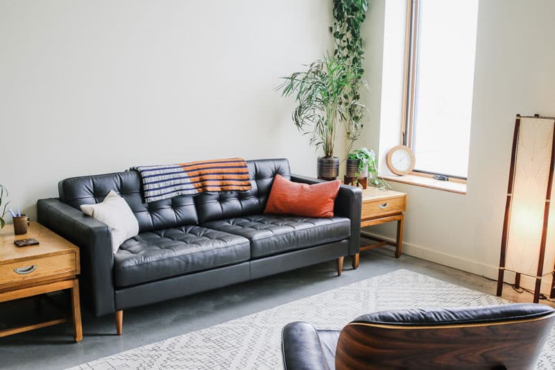 Somatic Center Portland lounge with a black leather sofa, side tables, plants and a floor lamp