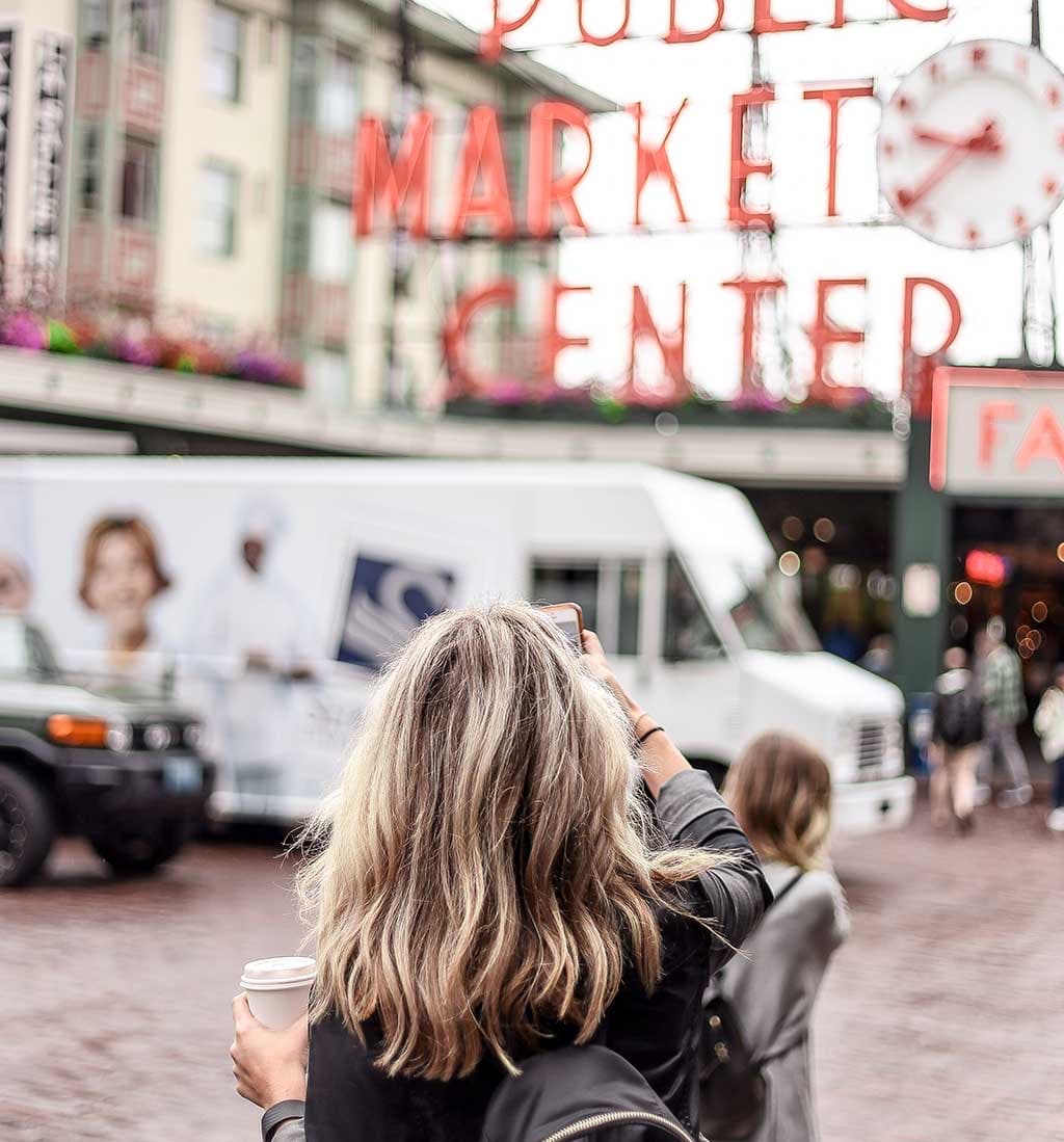 Shoppers under the Public Market Center sign at Pike Place Market in Seattle