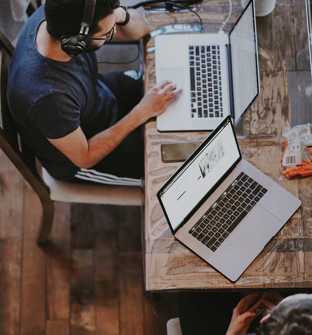 People working on laptops at a shared wooden table