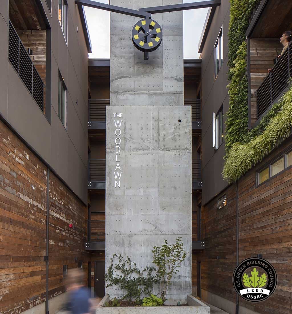 The Woodlawn courtyard entry in Portland: a concrete tower flanked by wood siding and living walls