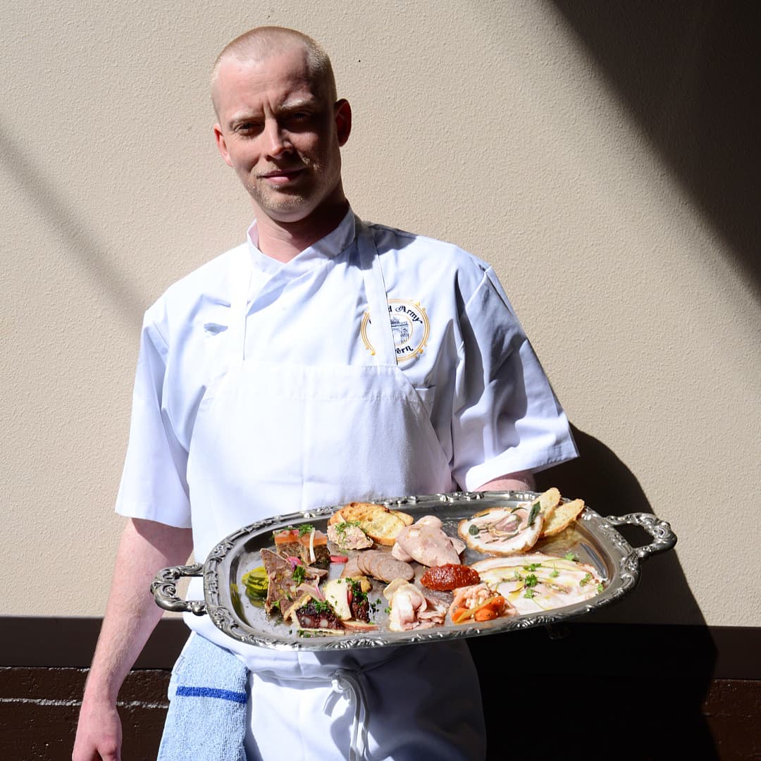 Grand Army Tavern chef in whites holding a silver platter of seafood and oysters